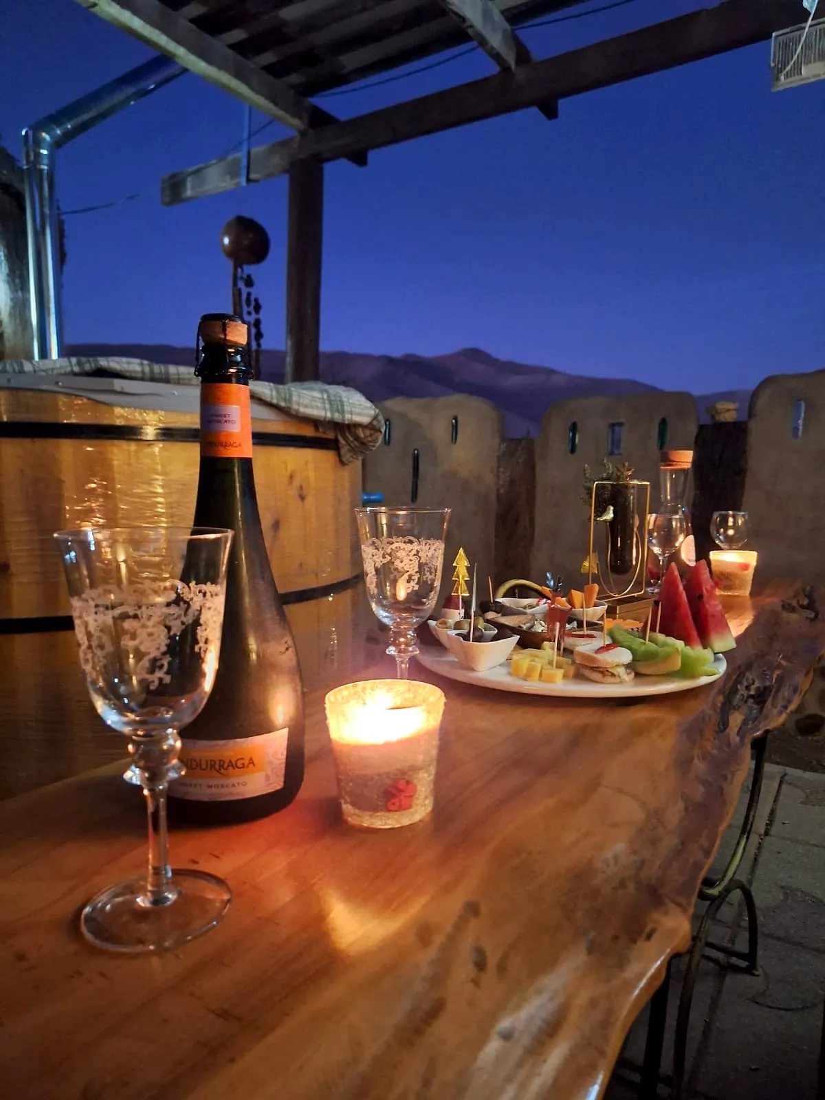 Tinaja de madera al atardecer, con espumante, una vela y la tabla servida